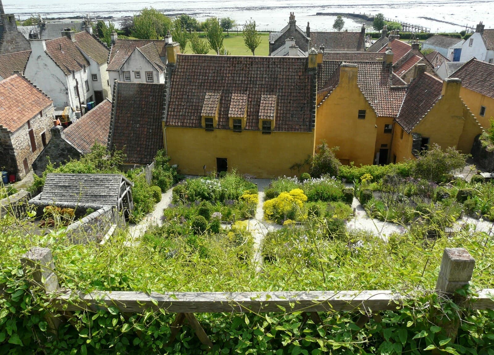 The ochre walls of Culross Palace behind terraced garden beds