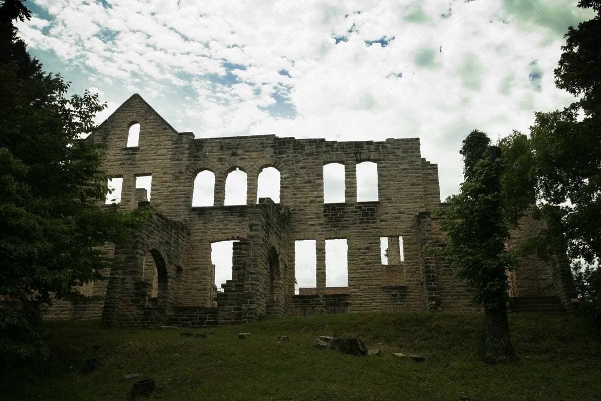 Roofless stone walls with empty window openings among trees