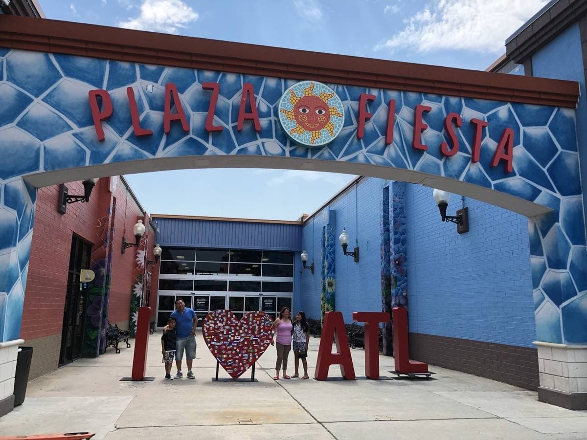A blue tiled entrance arch lettered Plaza Fiesta with a sun emblem