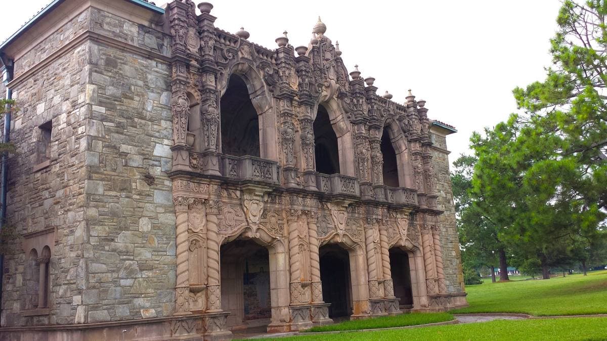 An ornate stone mausoleum facade with arched openings and carved tracery