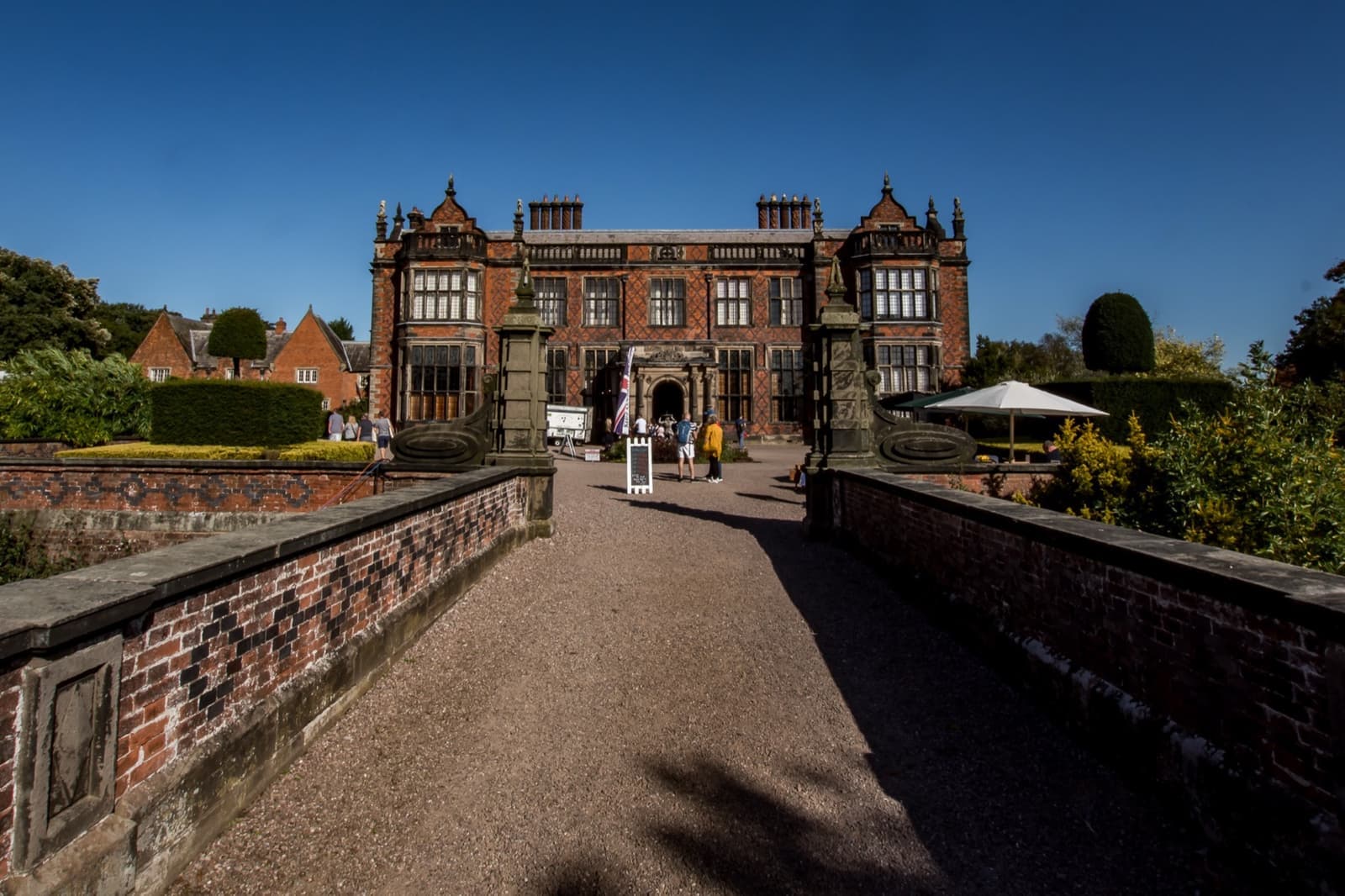 A brick Victorian hall at the end of a gravel drive between low walls