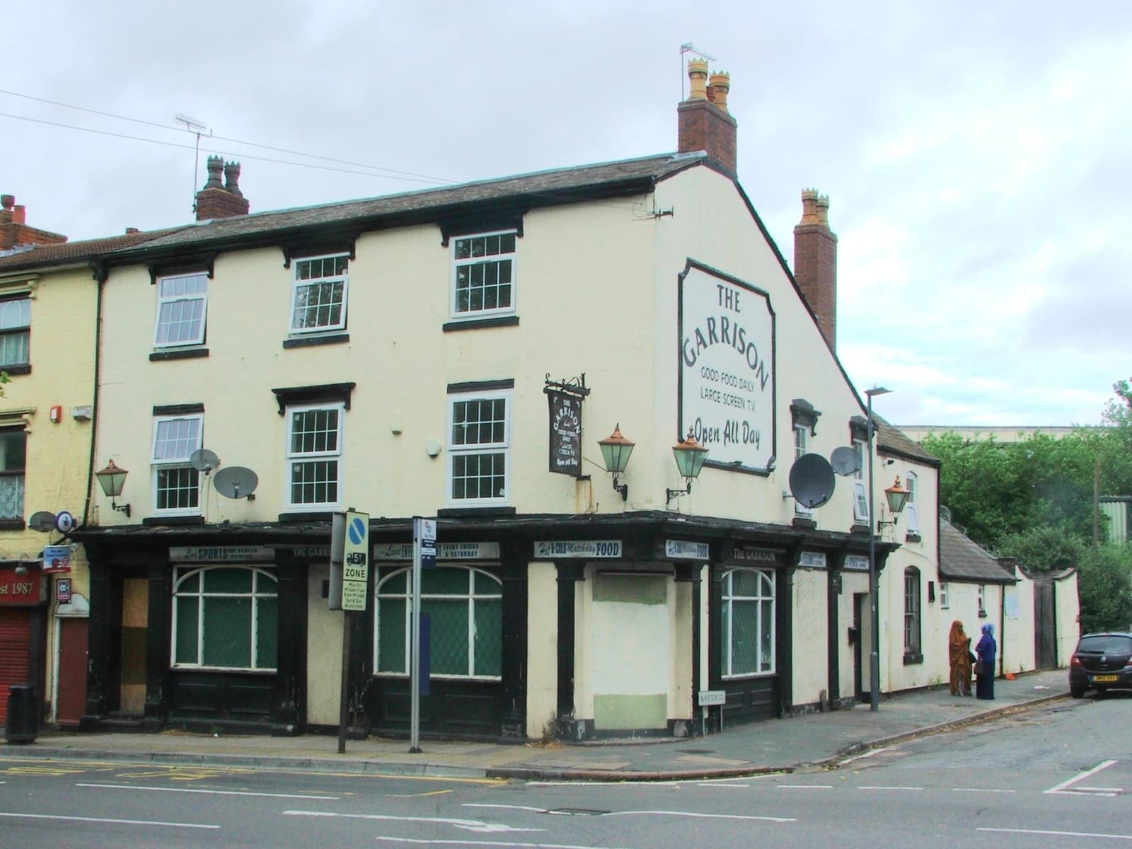 A cream-painted Victorian corner pub with a hanging sign