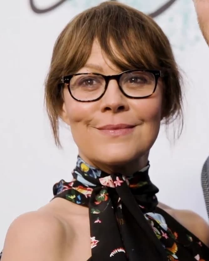 Helen McCrory smiling, in glasses and a dark floral top
