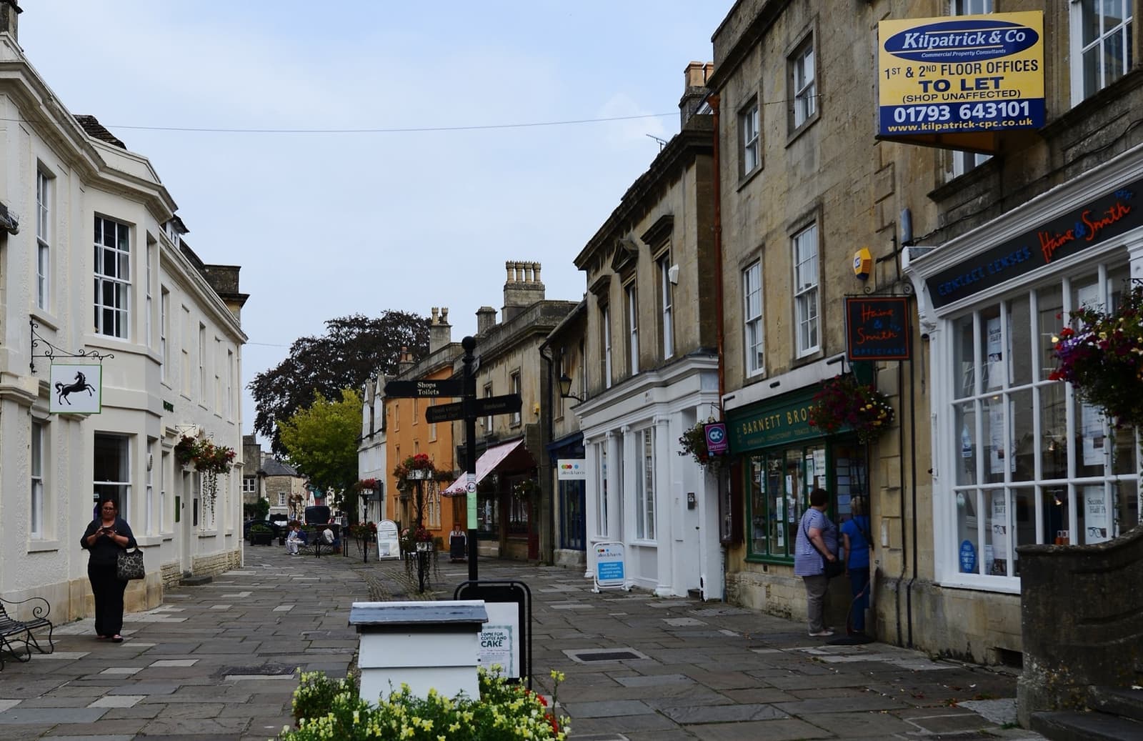 A paved street of stone shopfronts and Georgian houses