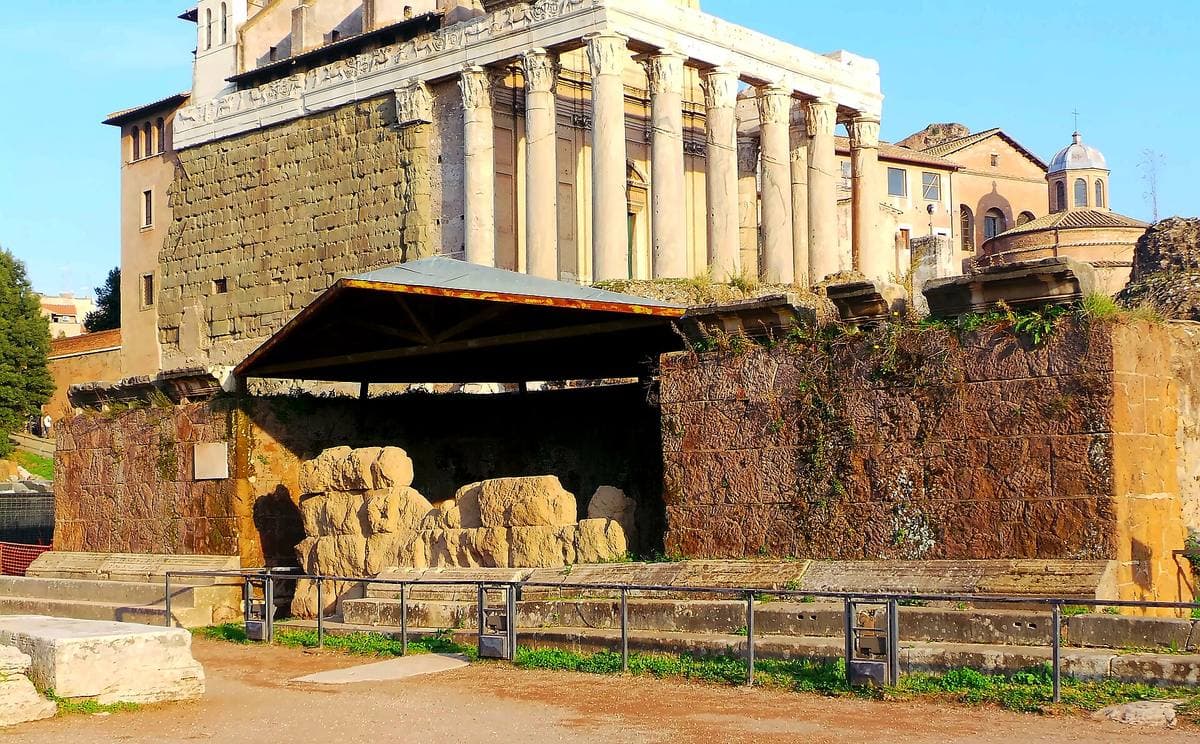 A low ruined podium under a modern roof in the Roman Forum