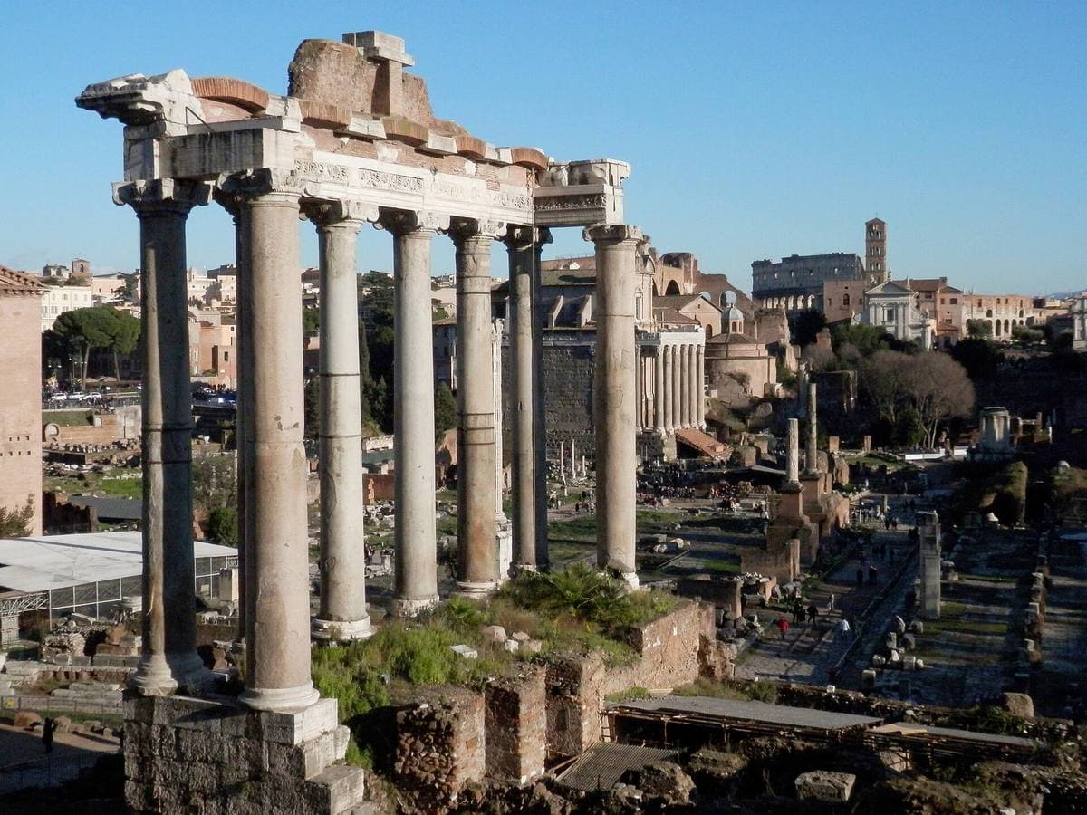 Ruined columns and arches of the Roman Forum with Rome beyond