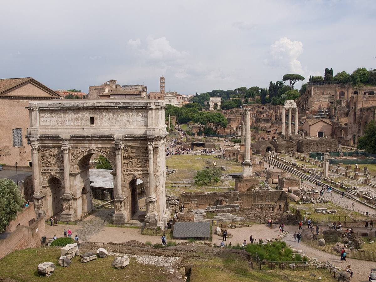 A wide view down the Roman Forum with a triumphal arch on the left
