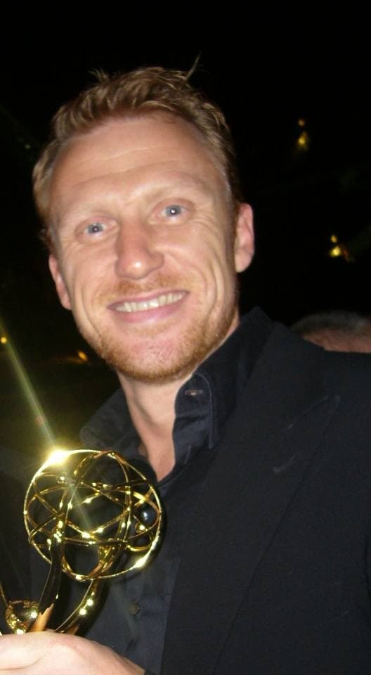 Kevin McKidd smiling in a dark suit