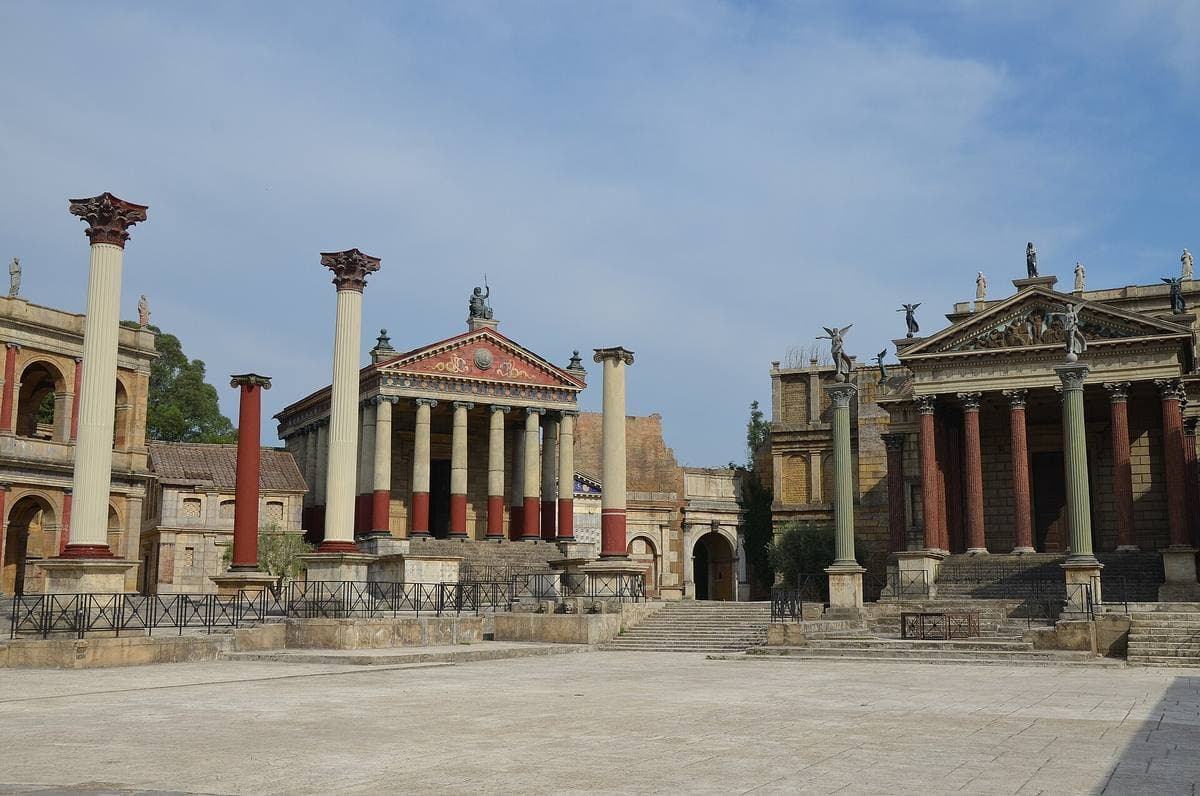 A wide square of temple fronts, columns and red-painted porticoes under a blue sky