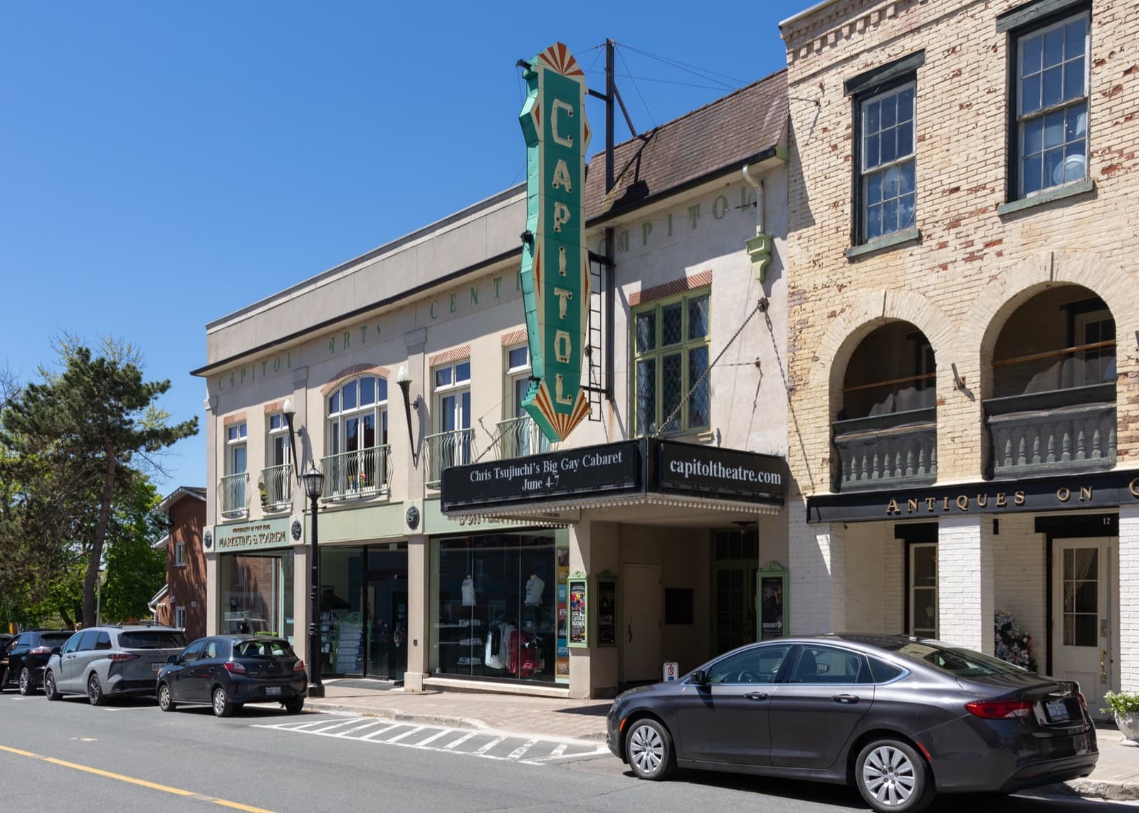 A theatre with a tall vertical sign in a row of brick and stone buildings