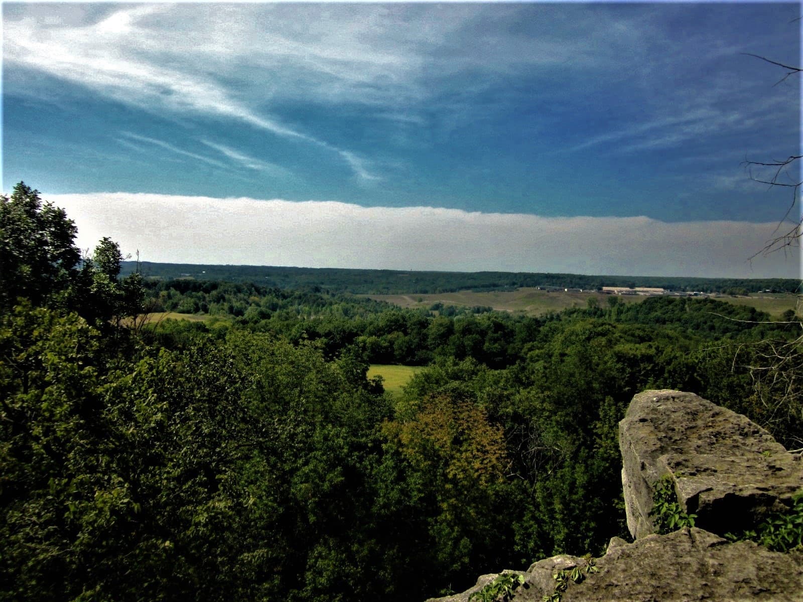 A limestone outcrop above a wide green valley under a streaked sky