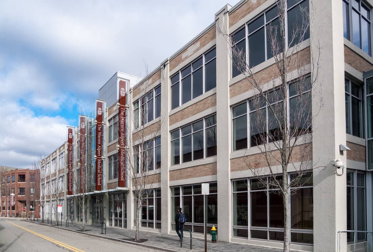 A long four-storey former factory of pale brick and big windows, now a medical school, on a winter street