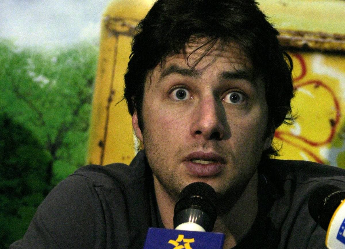 A young man with dark tousled hair and wide eyes leaning towards a microphone
