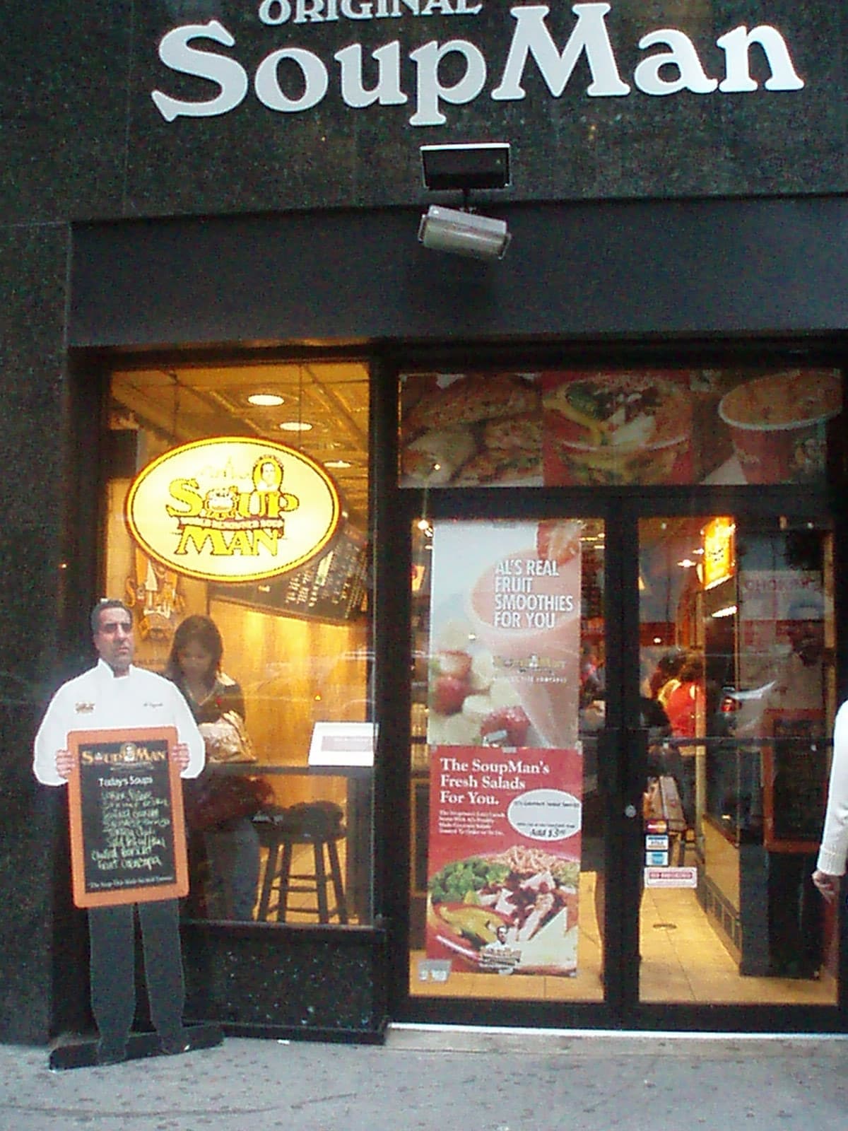 A narrow soup takeaway window on West 55th Street with menus posted around it