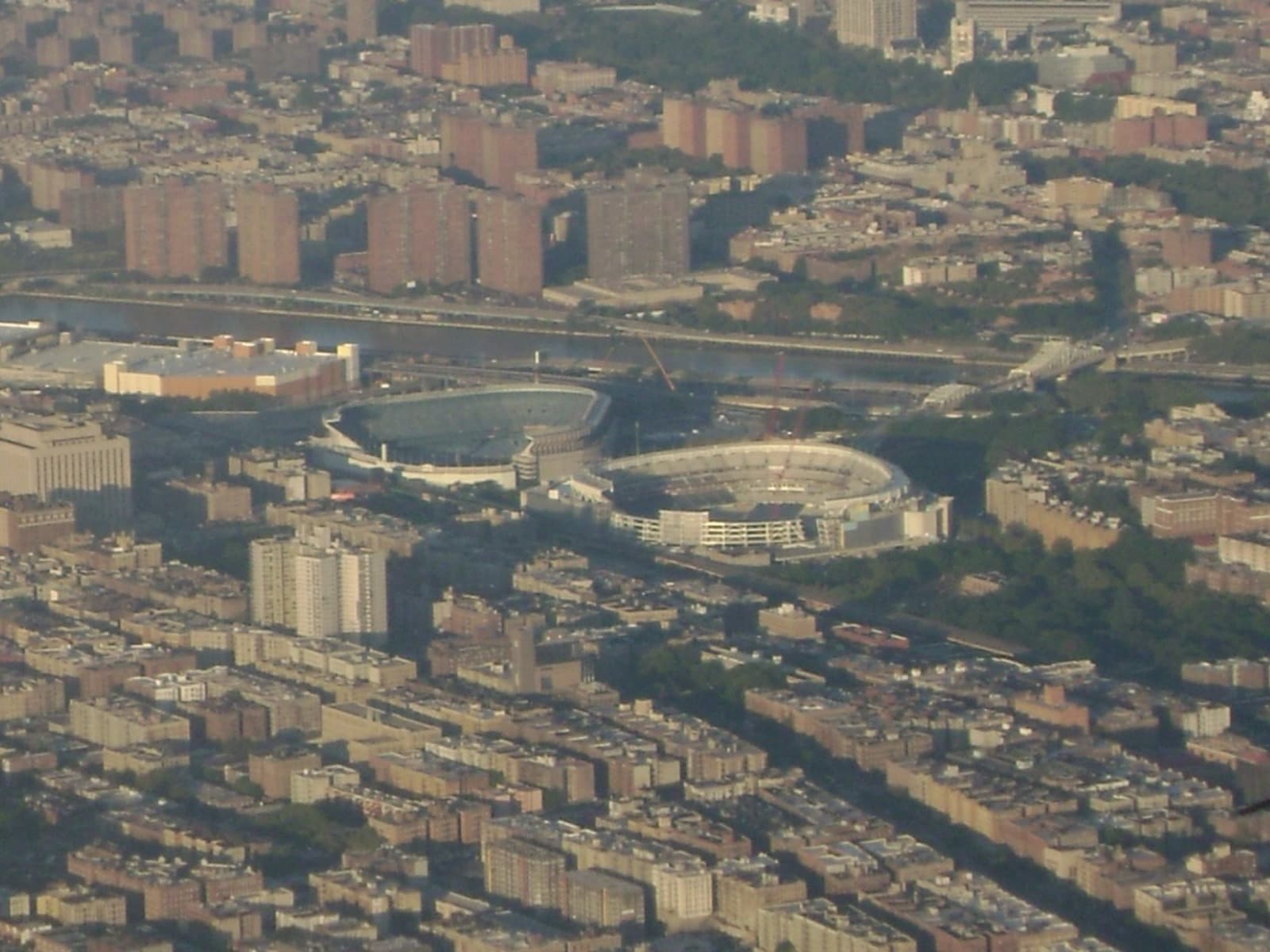 An aerial view of two stadiums across a street in the Bronx, the old one on the left