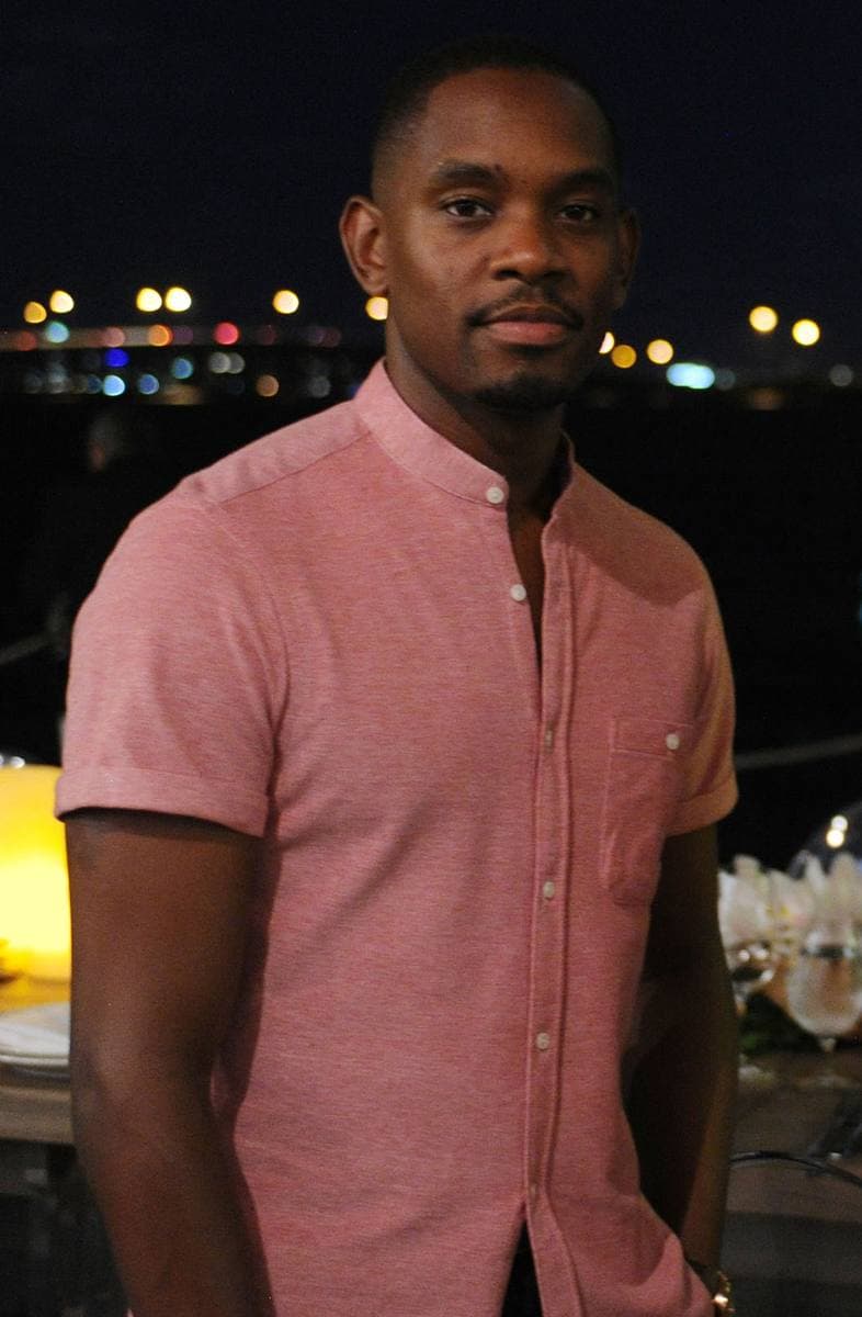 Aml Ameen in a pink shirt, standing outdoors at night