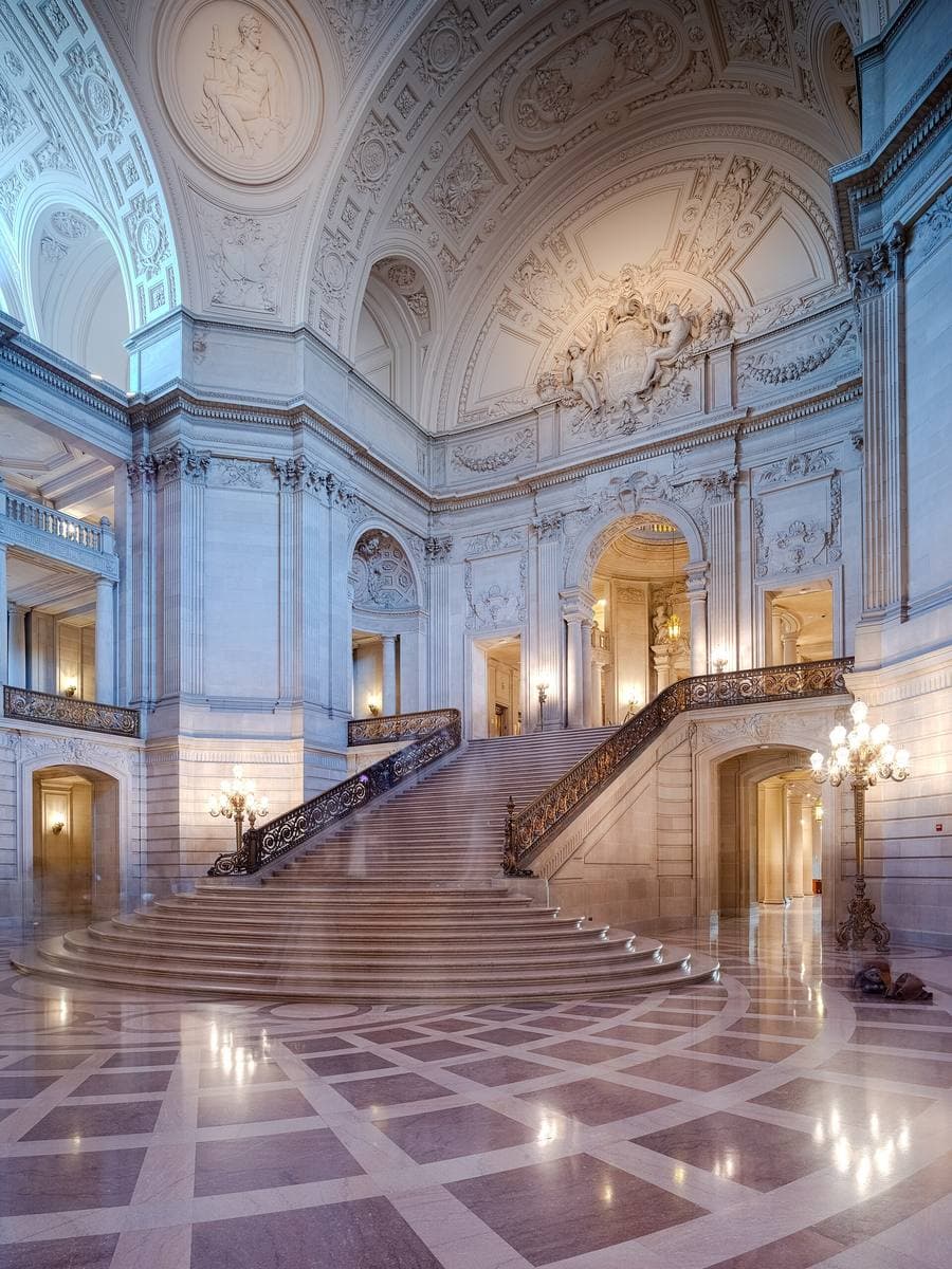 A sweeping marble staircase rising under a tall domed rotunda