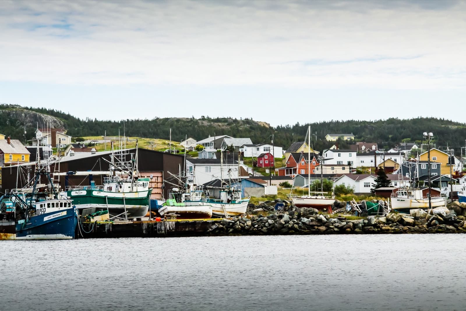 Painted wooden buildings and boats along a harbour front