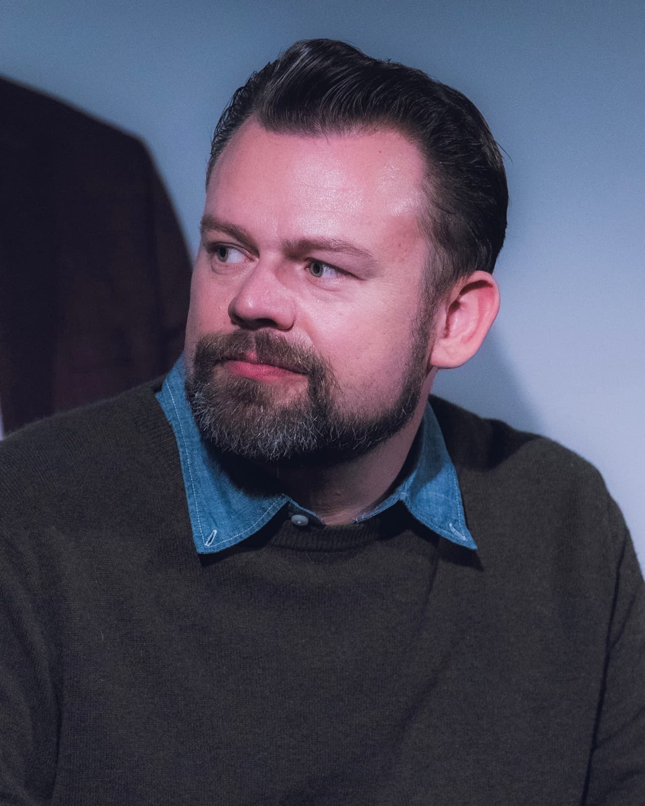 Dan Erickson, bearded, in a dark jumper over a denim shirt