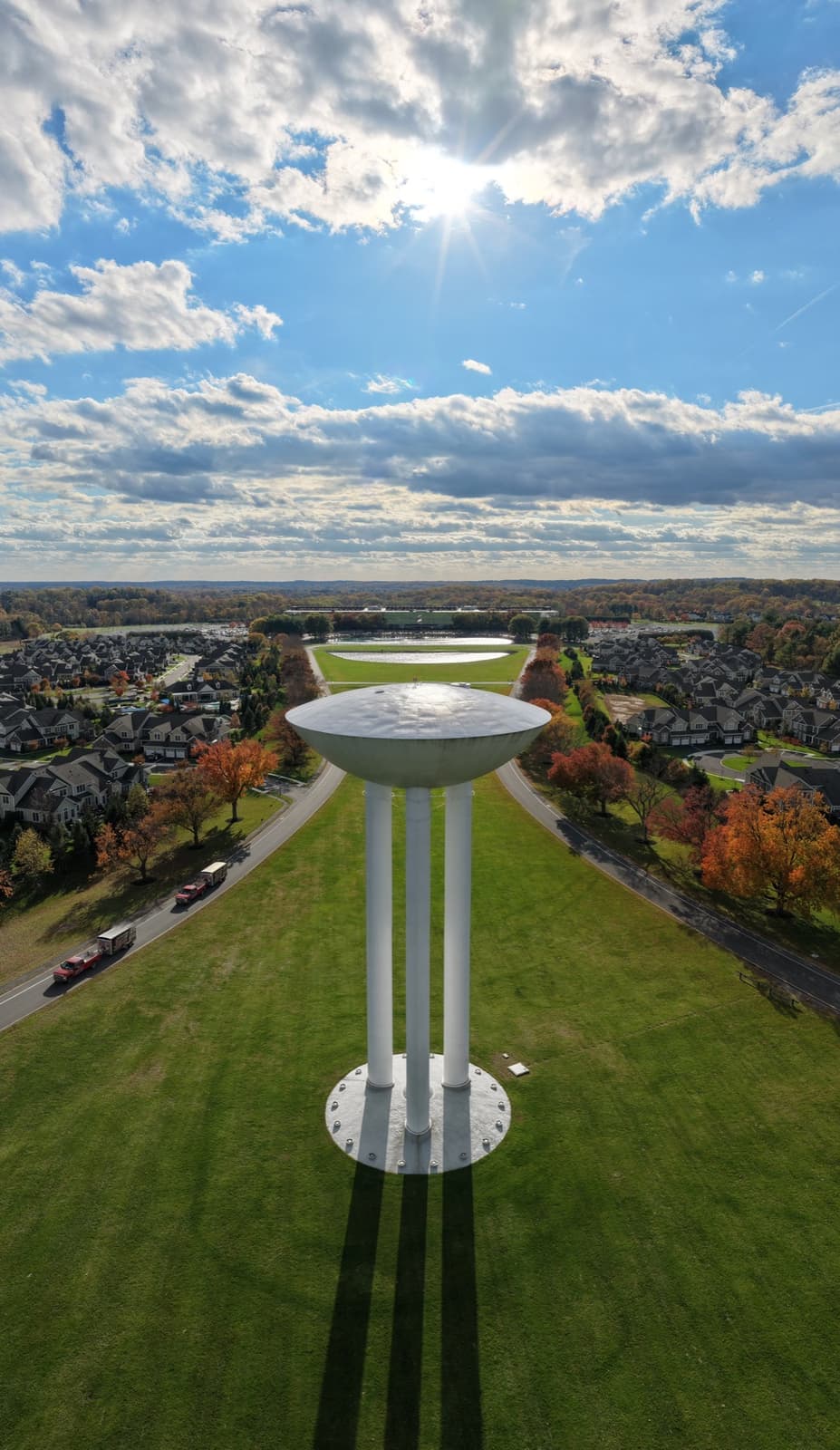 A white water tower shaped like a transistor on a lawn, seen from the air