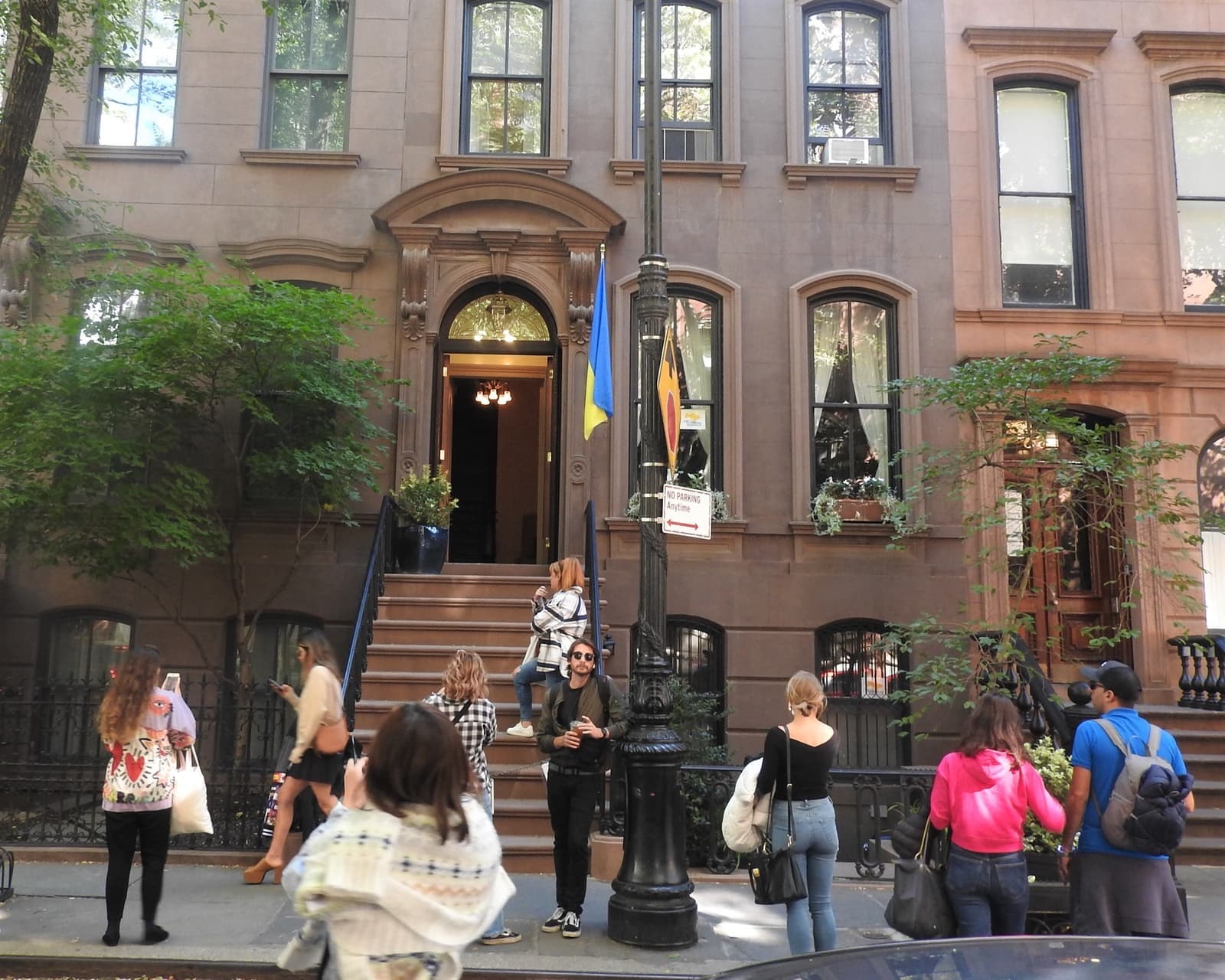 A brownstone stoop on Perry Street behind iron railings, a group of visitors on the pavement in front