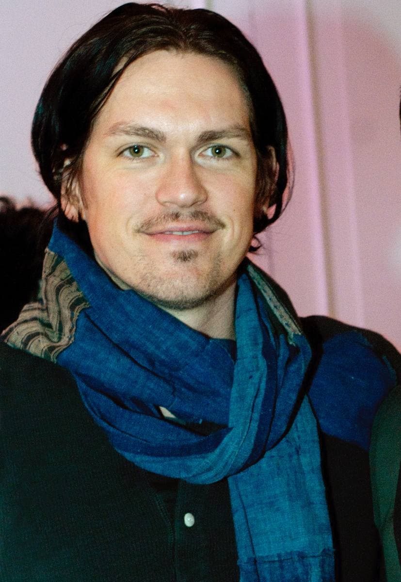 Steve Howey in a blue scarf, smiling