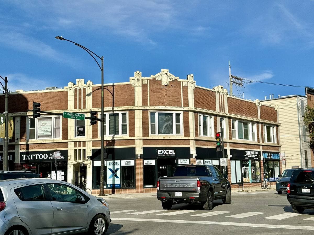 A two-storey brick and terracotta corner building with shops