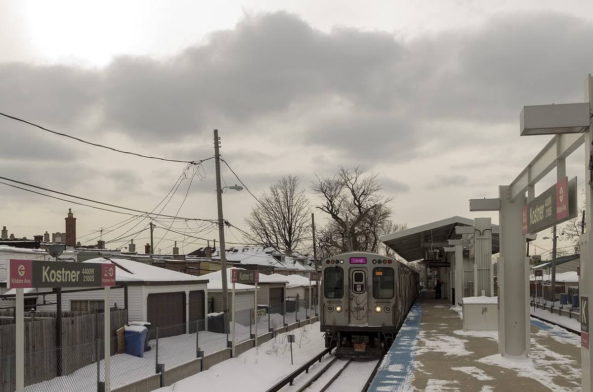 A Pink Line train at a snowy elevated stop under a grey sky