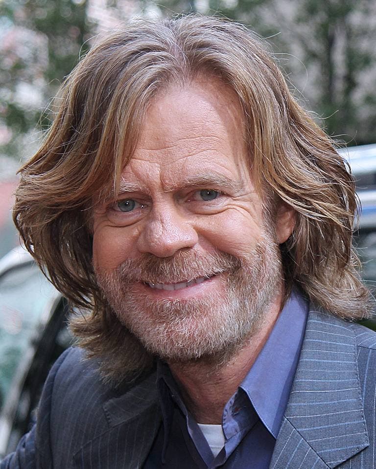 William H. Macy smiling, grey-blond hair swept back, in a dark jacket