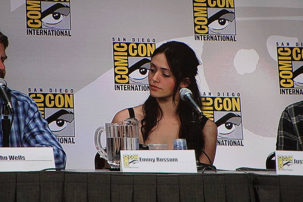 Emmy Rossum at a panel table with a name card and microphone