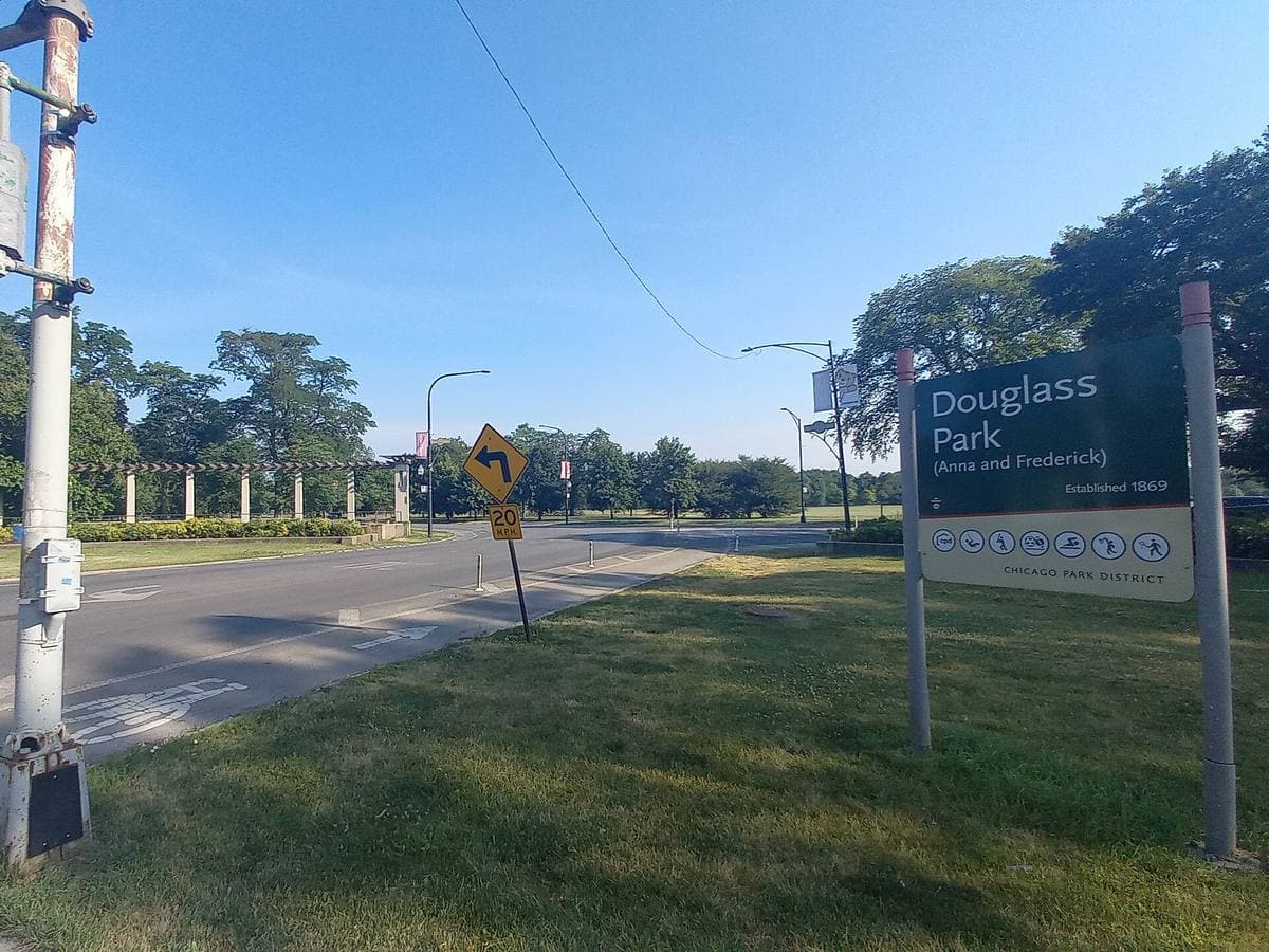 A park drive with lawns and trees and a Douglass Park sign