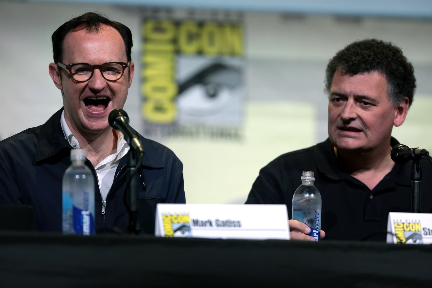 Mark Gatiss laughing and Steven Moffat speaking at a panel table