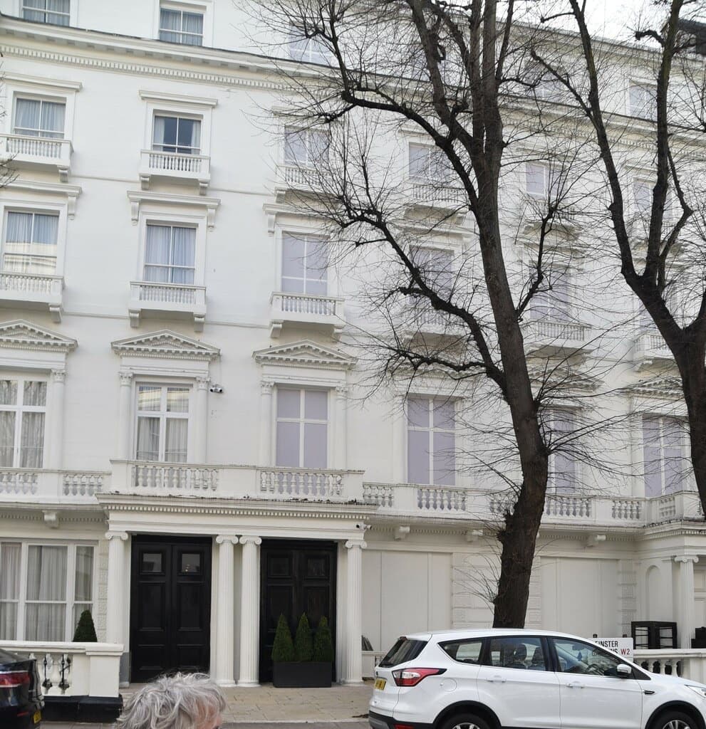 A white stucco terrace with two black front doors and balustraded windows