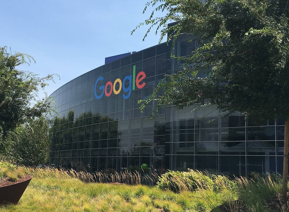 A low glass and steel office building with a coloured sign in front
