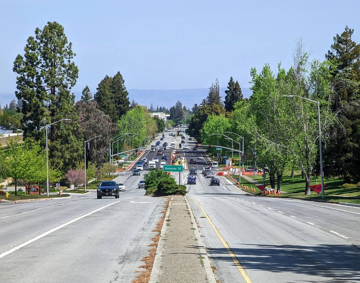 A wide road with a median running downhill between trees