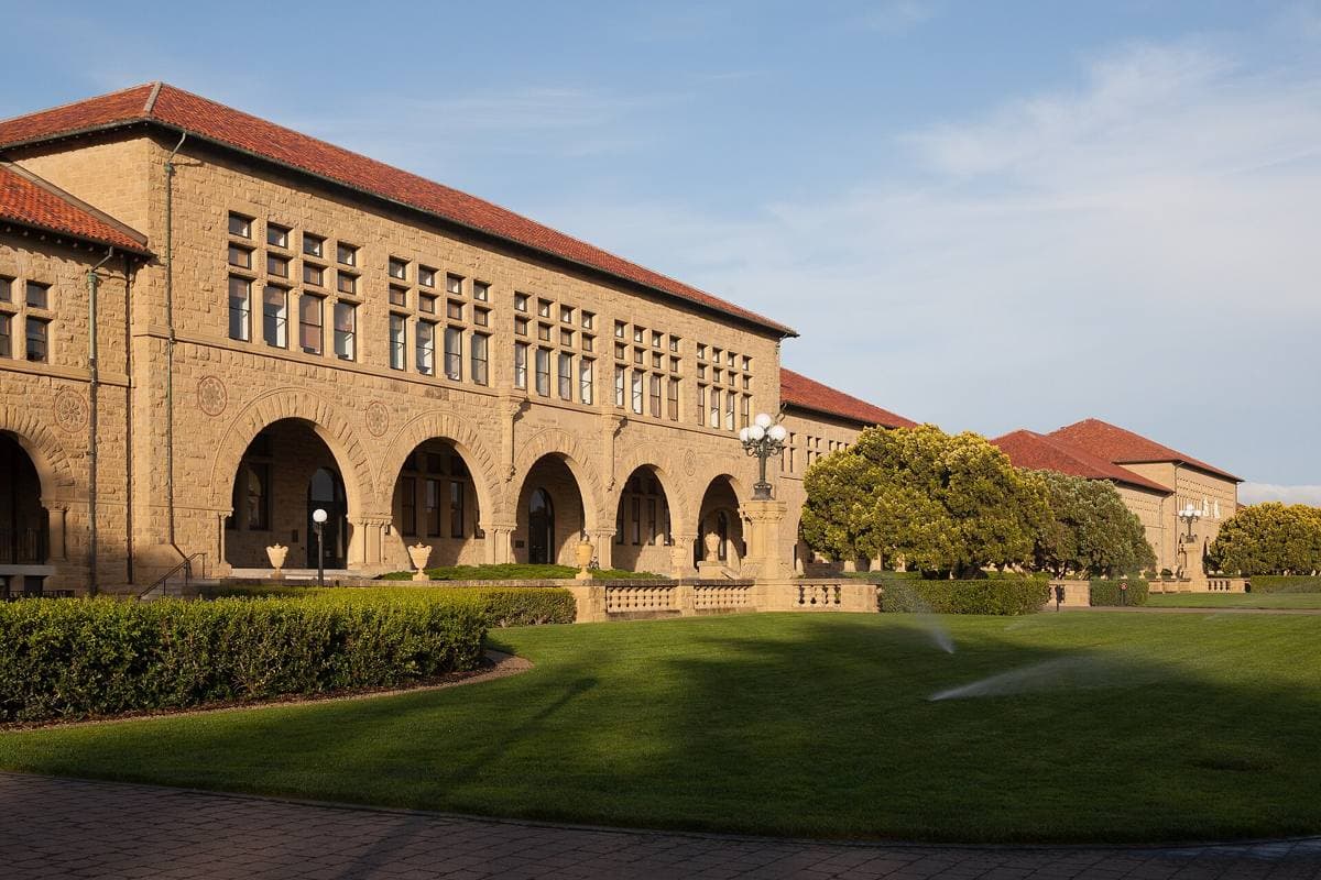 A sandstone building with arches and a red tile roof