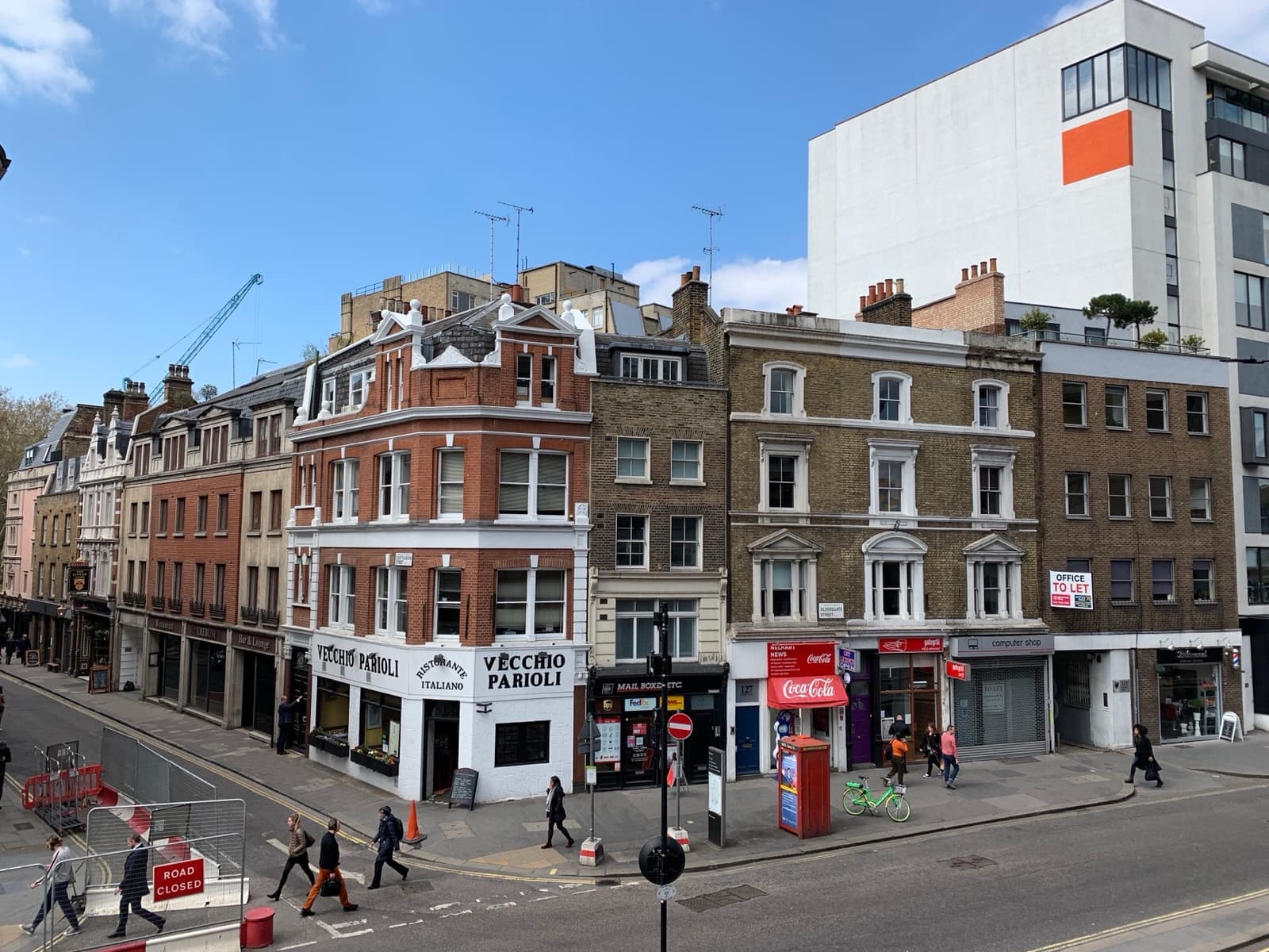 A row of old brick buildings on a street corner, the Vecchio Parioli restaurant on the ground floor and a red phone box in front