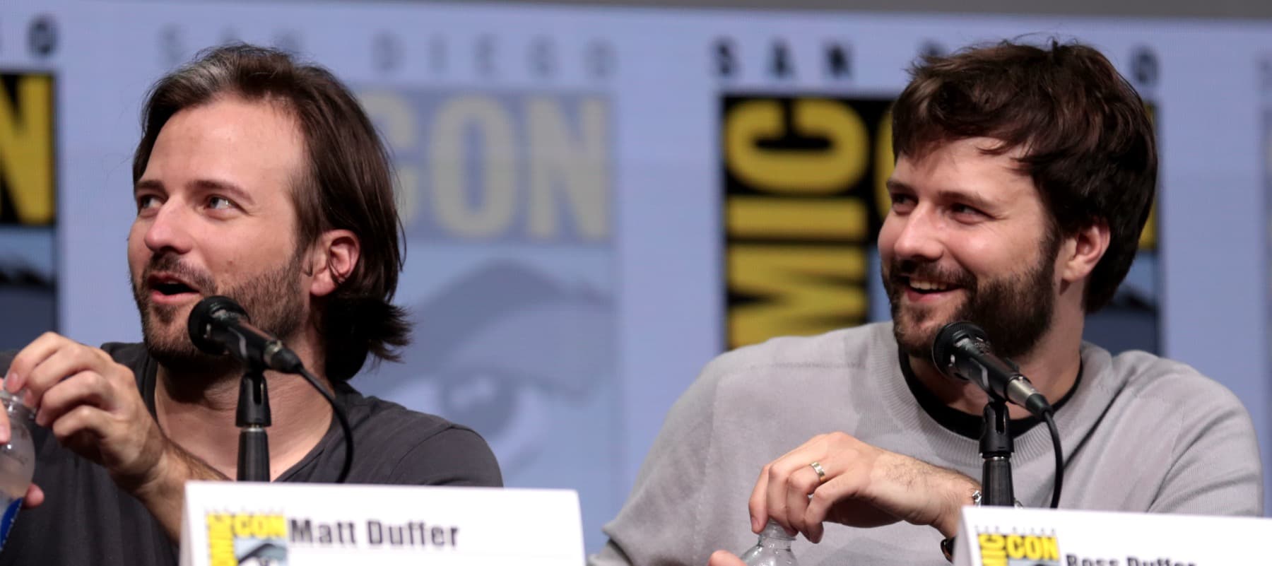 The twin creators Matt and Ross Duffer laughing at a panel table