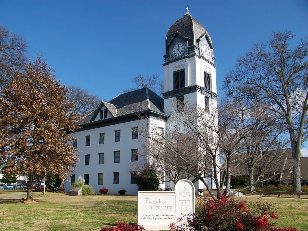 A white courthouse with a cupola behind trees