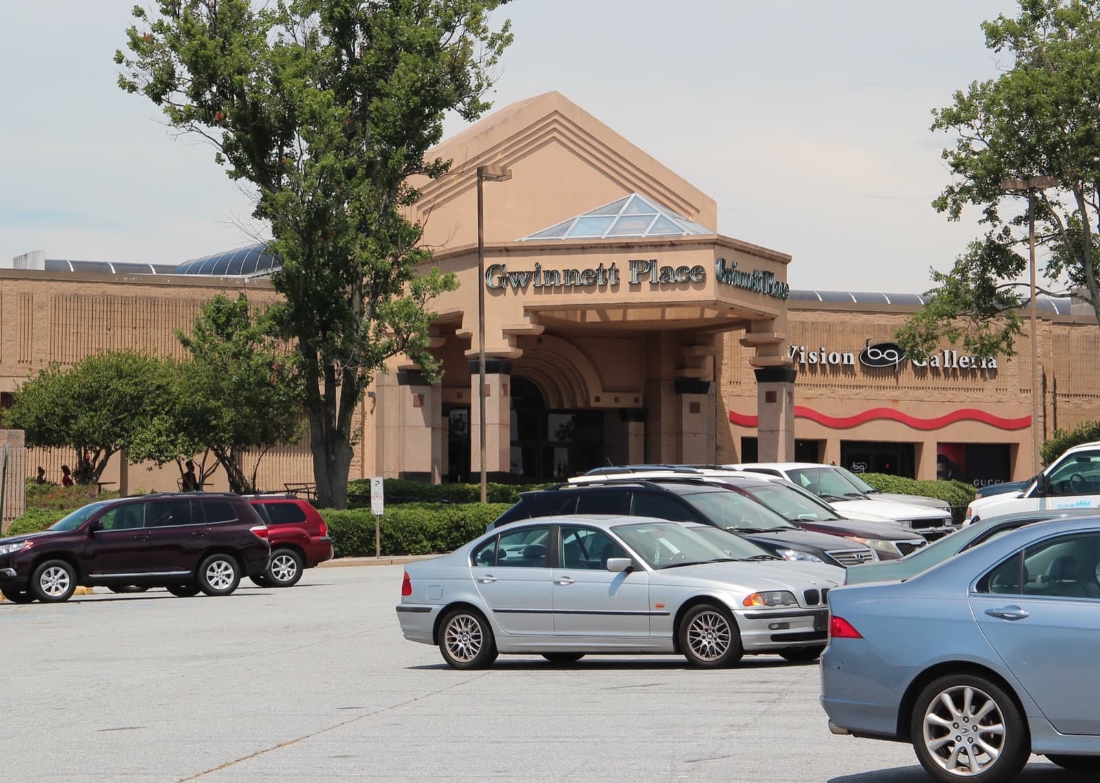 A beige mall entrance with a domed skylight behind a car park