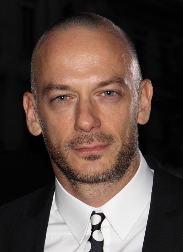 Filippo Nigro, shaven-headed, in a white shirt and black tie