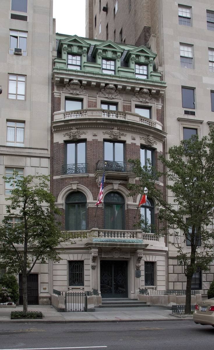 A narrow Beaux-Arts townhouse of brick and limestone with a green mansard roof on Fifth Avenue