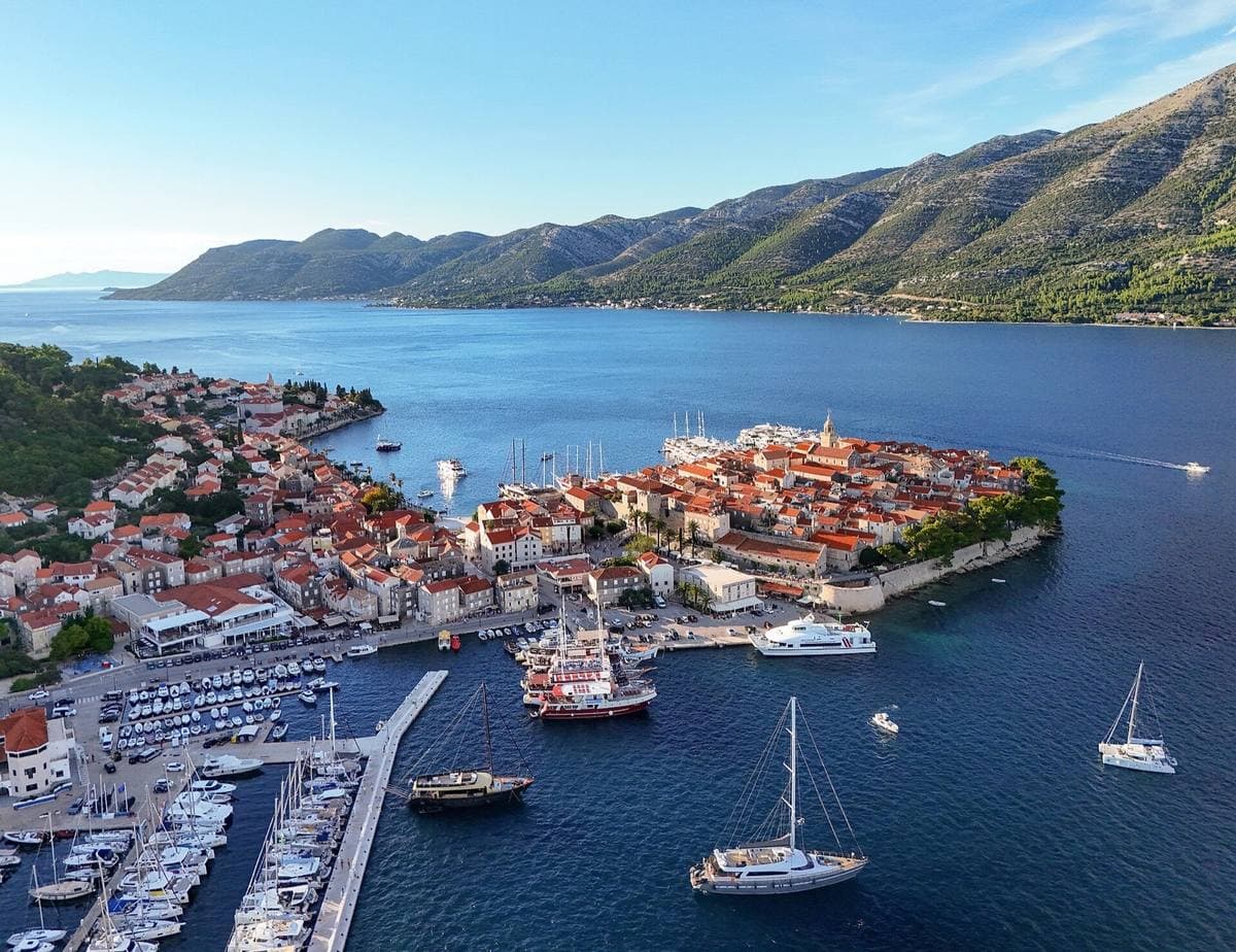Korčula’s walled old town on its peninsula, red roofs and a harbour of yachts, with mountains across the channel