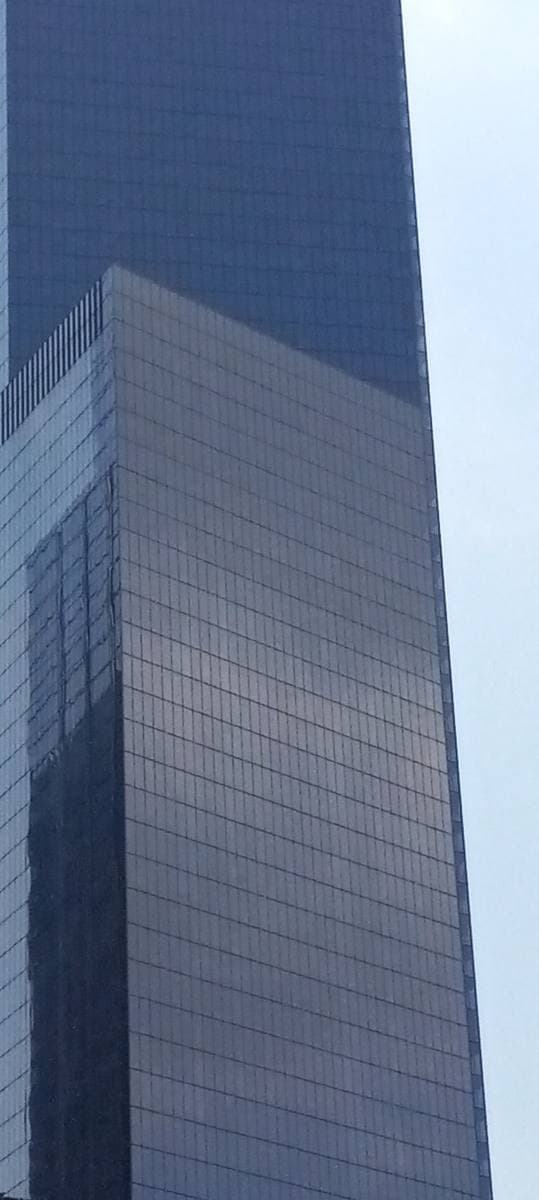 The dark glass flank of 4 World Trade Center rising into a pale sky