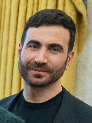 Brett Goldstein, bearded, in a dark suit