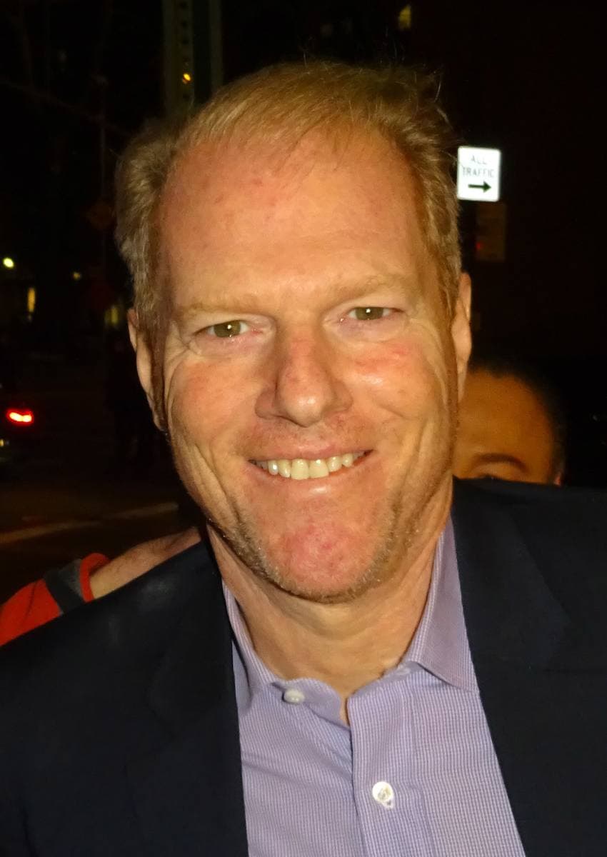 Noah Emmerich smiling in a pale blue shirt at night