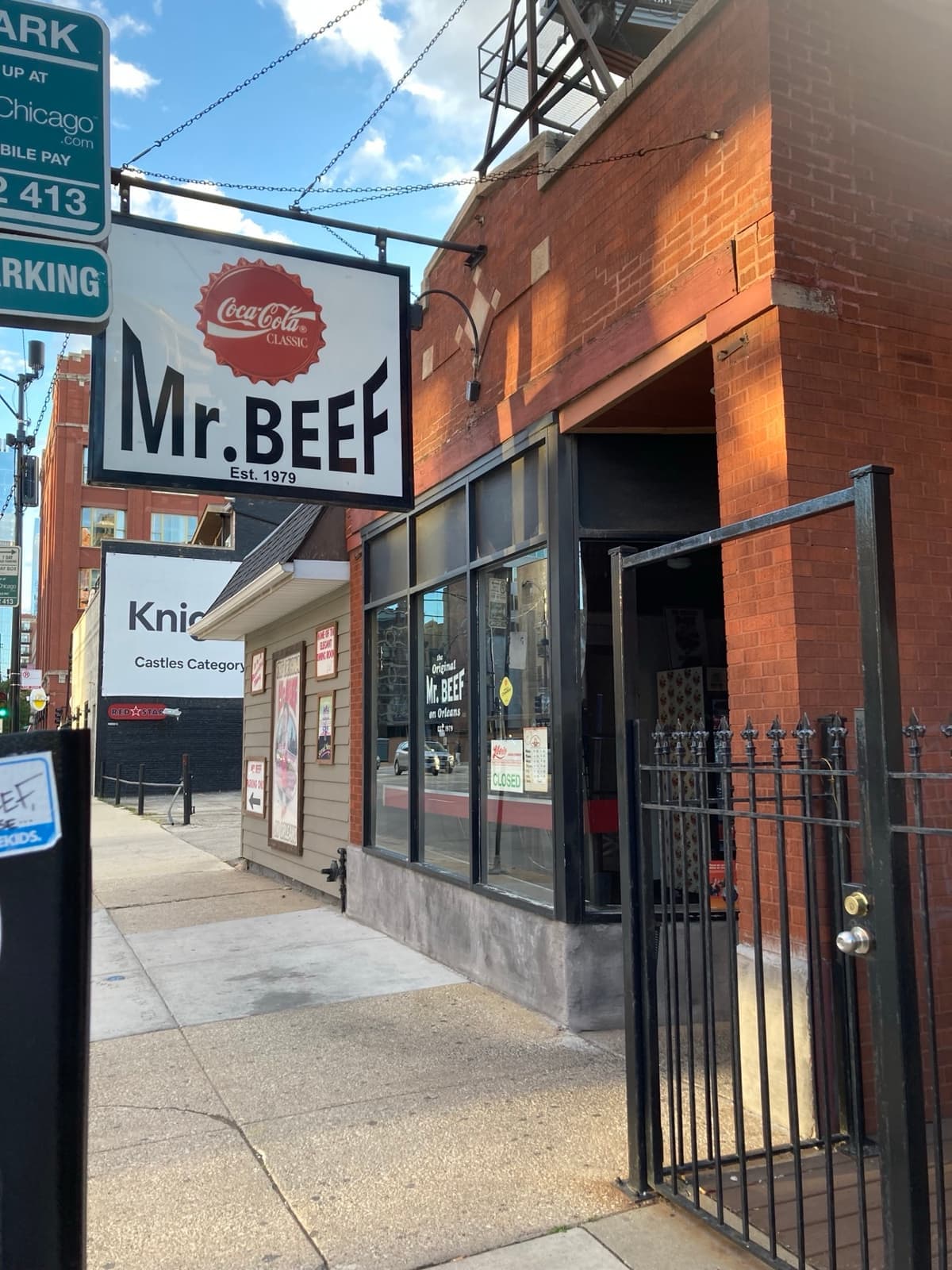 The Mr. Beef sign on a brick front on Orleans Street, with a black iron gate and a doorway open to the pavement