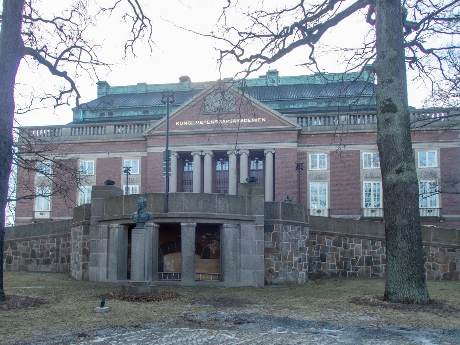 A red-brick classical building with columns behind bare trees