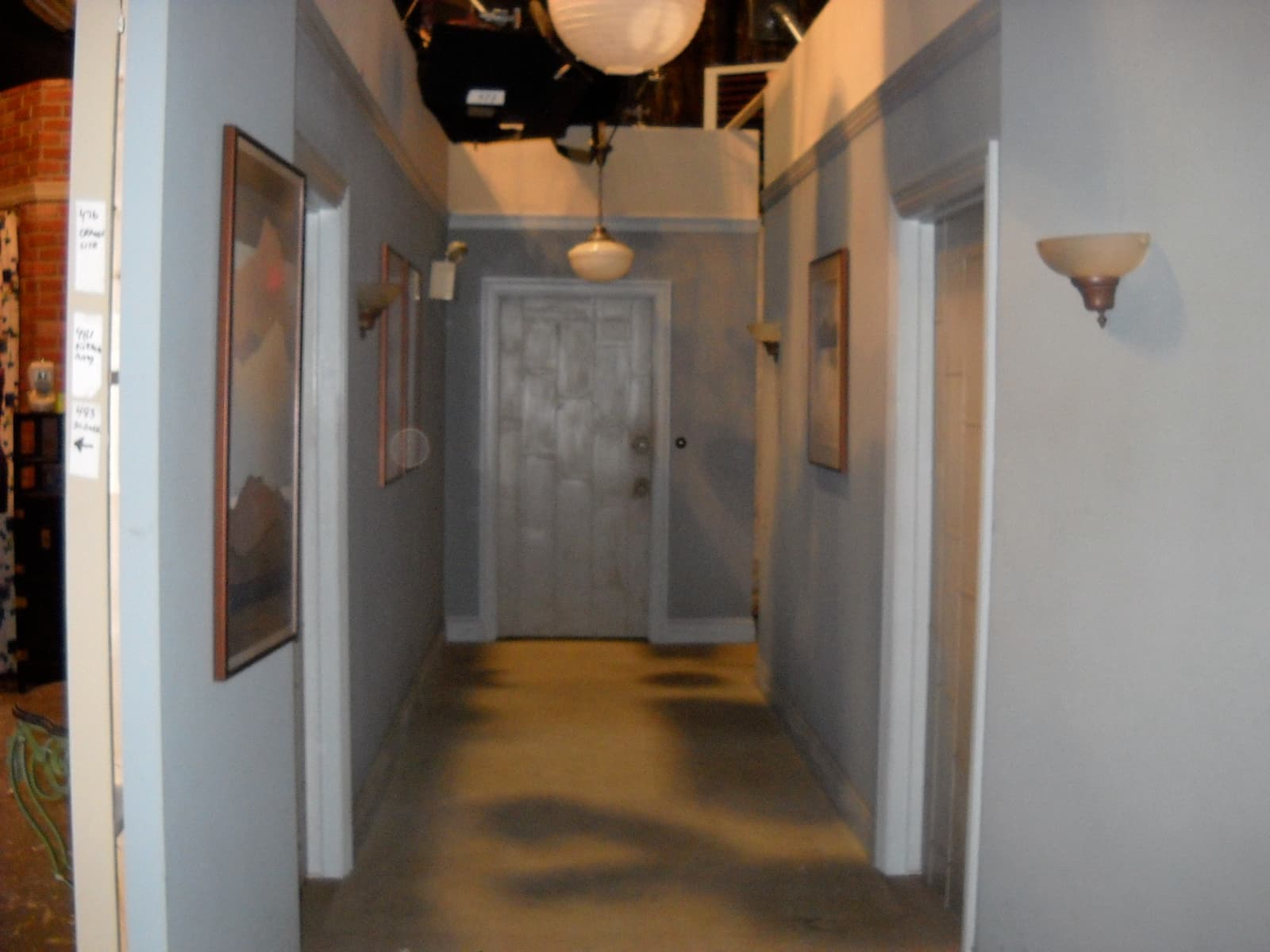 A narrow beige corridor with wall lamps and a closed door at the end