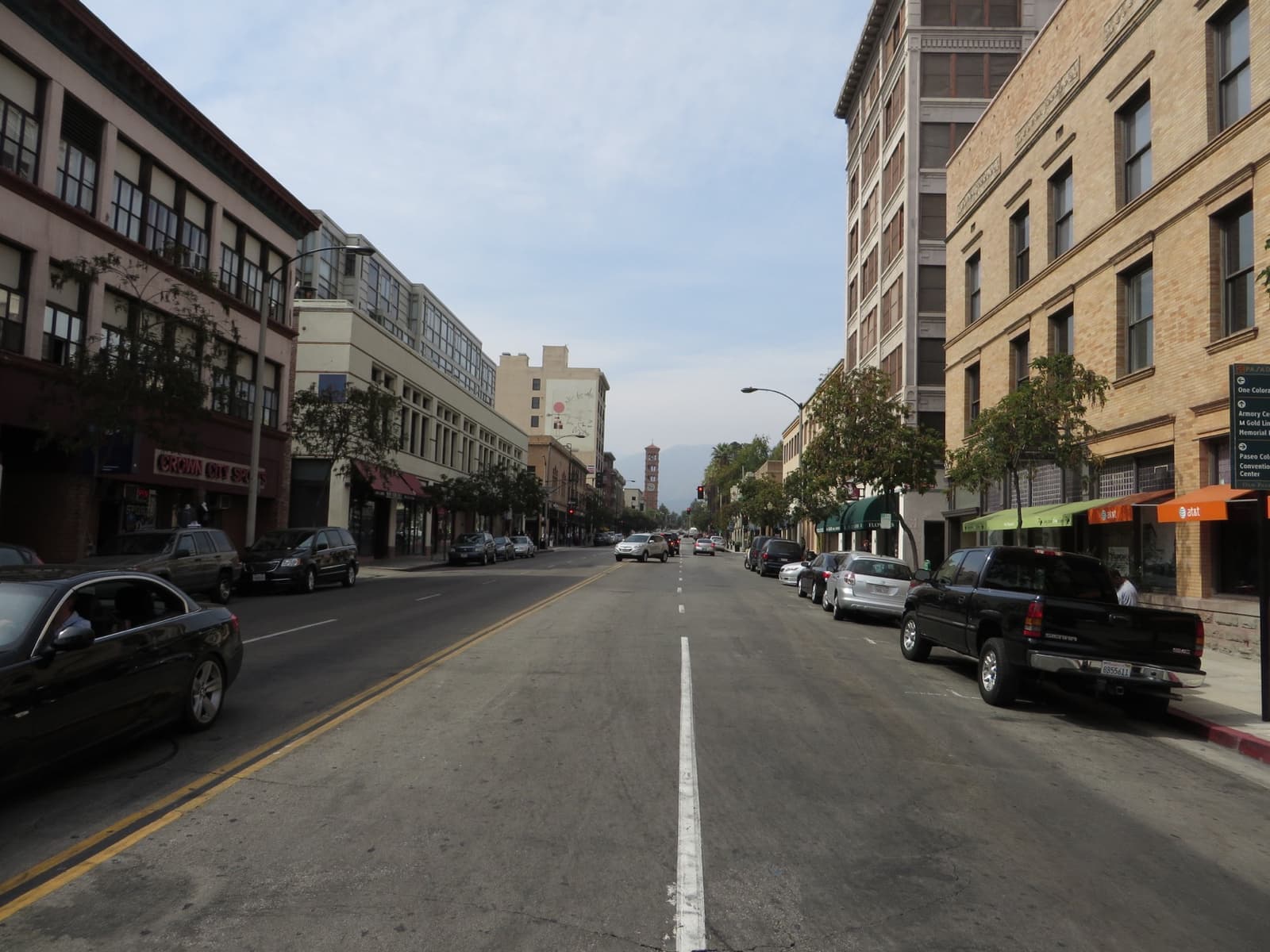 A straight Old Pasadena street of brick and stone buildings under a pale sky